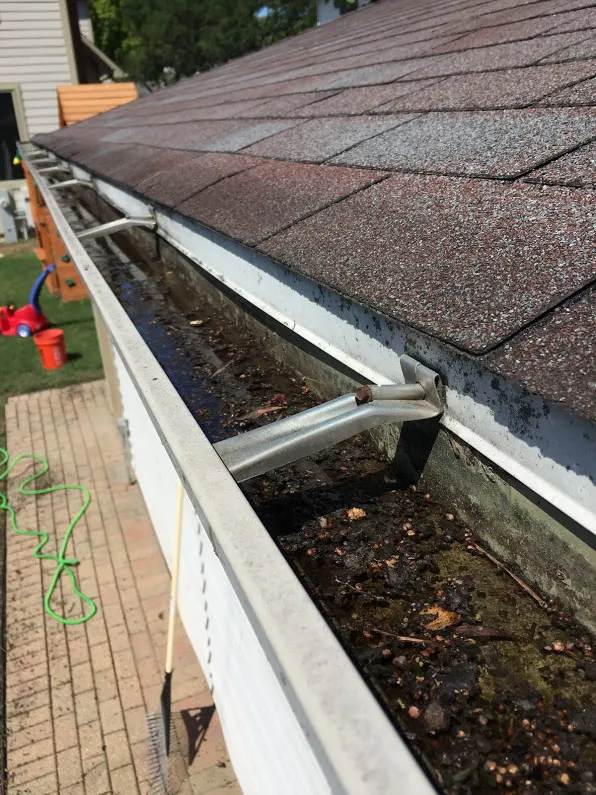 Standing water in a clogged gutter, indicating drainage issues and potential roof damage