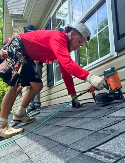 Triumph Roofing technician using a nail gun to install asphalt shingles on a residential roof in Charlotte, NC
